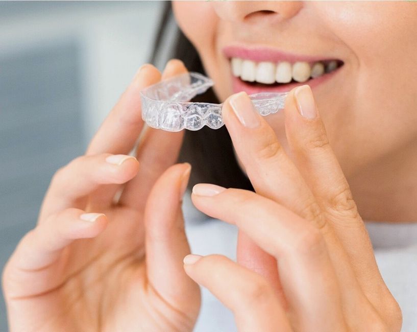 adult holding a clear Invisalign aligner
